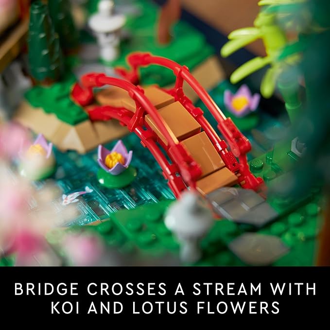 A red bridge spans a stream adorned with koi fish and blooming lotus flowers in a detailed LEGO garden scene.