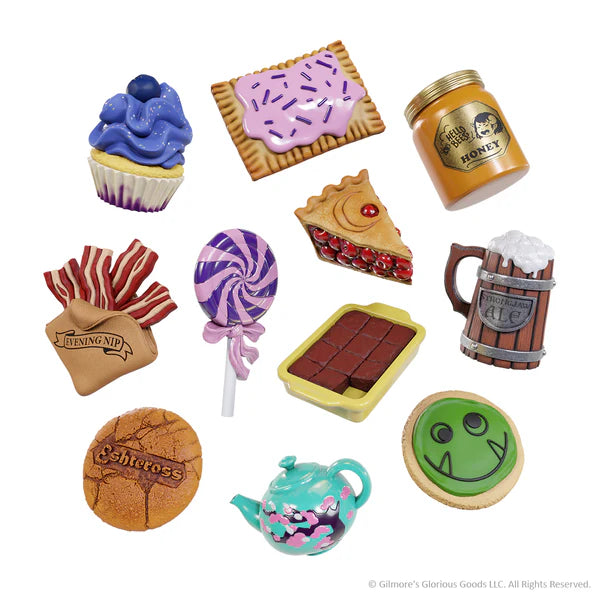 Colorful assortment of miniature food charms from Critical Role, including cupcakes, cookies, and a honey jar.