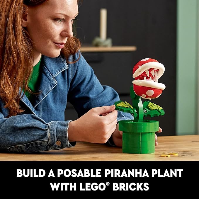 A person builds a posable LEGO Piranha Plant model, showcasing vibrant green and red bricks on a wooden table.