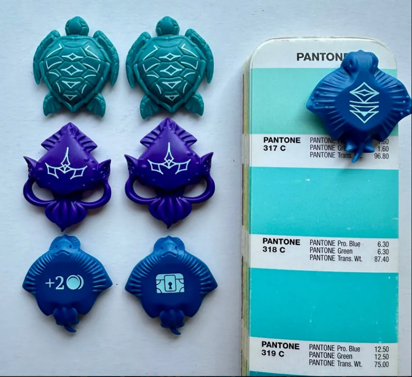 Aquatica Duellum preorder tokens in blue and purple, featuring turtles and icons, alongside a Pantone color guide.
