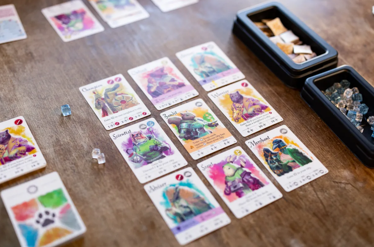 Colorful game cards from "Citizens of the Spark" displayed on a wooden table, featuring various characters and abilities.