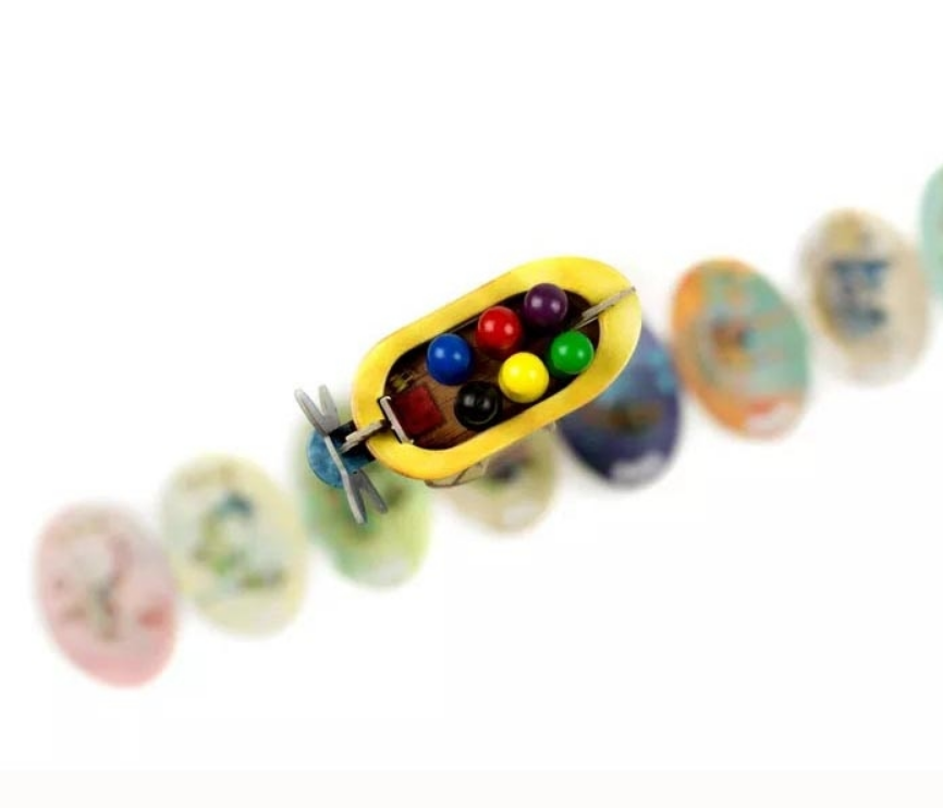 Colorful game pieces and a yellow game board element from the Celestia board game, showcasing a whimsical design.