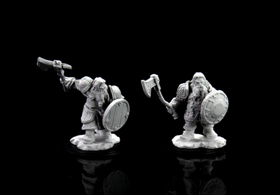 Unpainted miniatures of a male dwarf fighter, one wielding an axe and shield, the other with a hammer and shield.