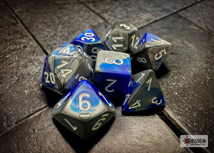 Chessex Gemini Blue/Steel 7-die set featuring blue and gray dice with silver numbers, ideal for tabletop gaming.