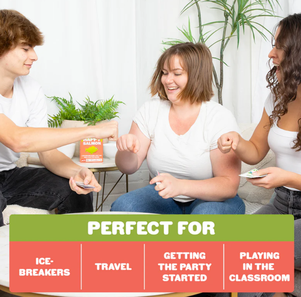 Three friends play Grab & Game: Happy Salmon, laughing and engaging in a fun card game on a cozy living room set.