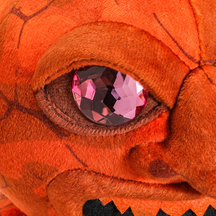 Close-up of a plush Dungeons & Dragons Sacred Statue featuring vibrant orange fabric and a sparkling pink gem eye.
