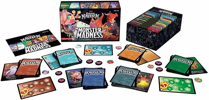 Colorful box of Dungeon Mayhem: Monster Madness with game cards, tokens, and player boards spread out on a table.