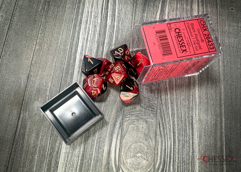 Chessex Gemini Black-Red/Gold Polyhedral 7-Dice Set in a clear box, featuring seven dice with gold numbers on a black-red swirl.