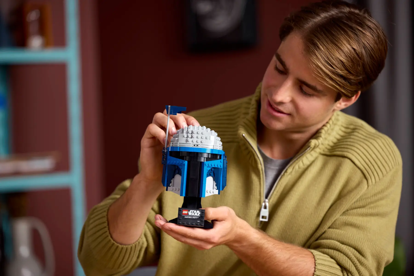 A person holds the LEGO Star Wars: Jango Fett Helmet (75408), showcasing its detailed design and vibrant colors.