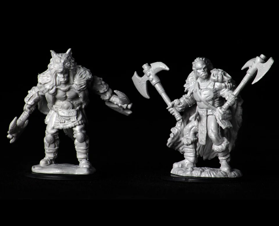 Unpainted miniatures of a male half-orc barbarian and a warrior holding dual axes, ideal for Dungeons & Dragons gameplay.