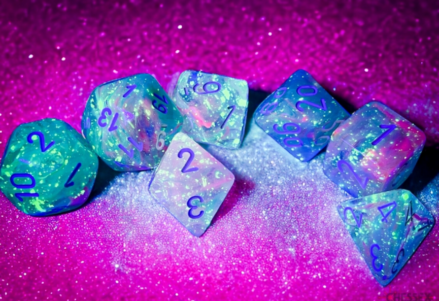 Chessex Nebula Wisteria White Luminary 7 Die Set featuring colorful, translucent dice with blue numbers on a sparkly background.