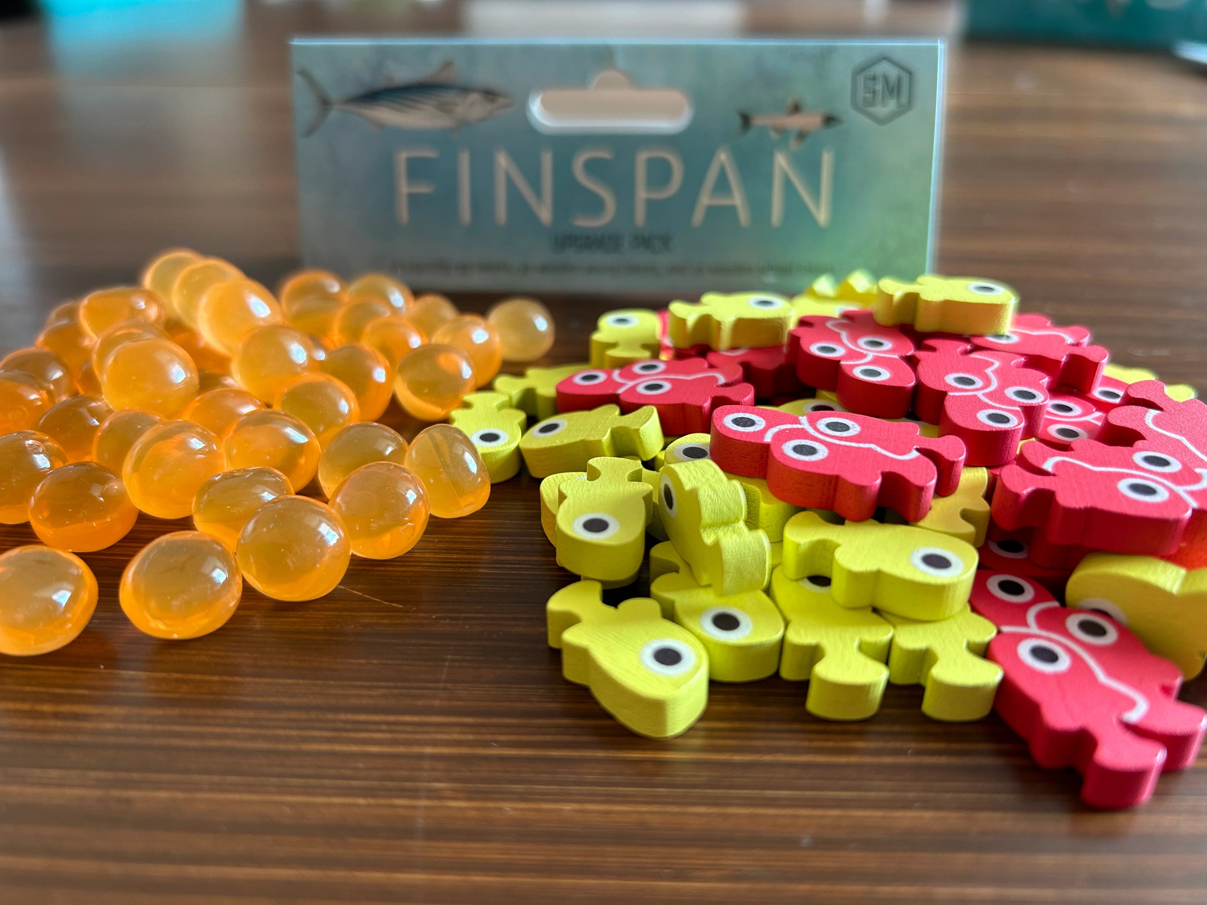 Colorful wooden tokens and squishy eggs from the Finspan Upgrade Pack, enhancing gameplay with vibrant game pieces.