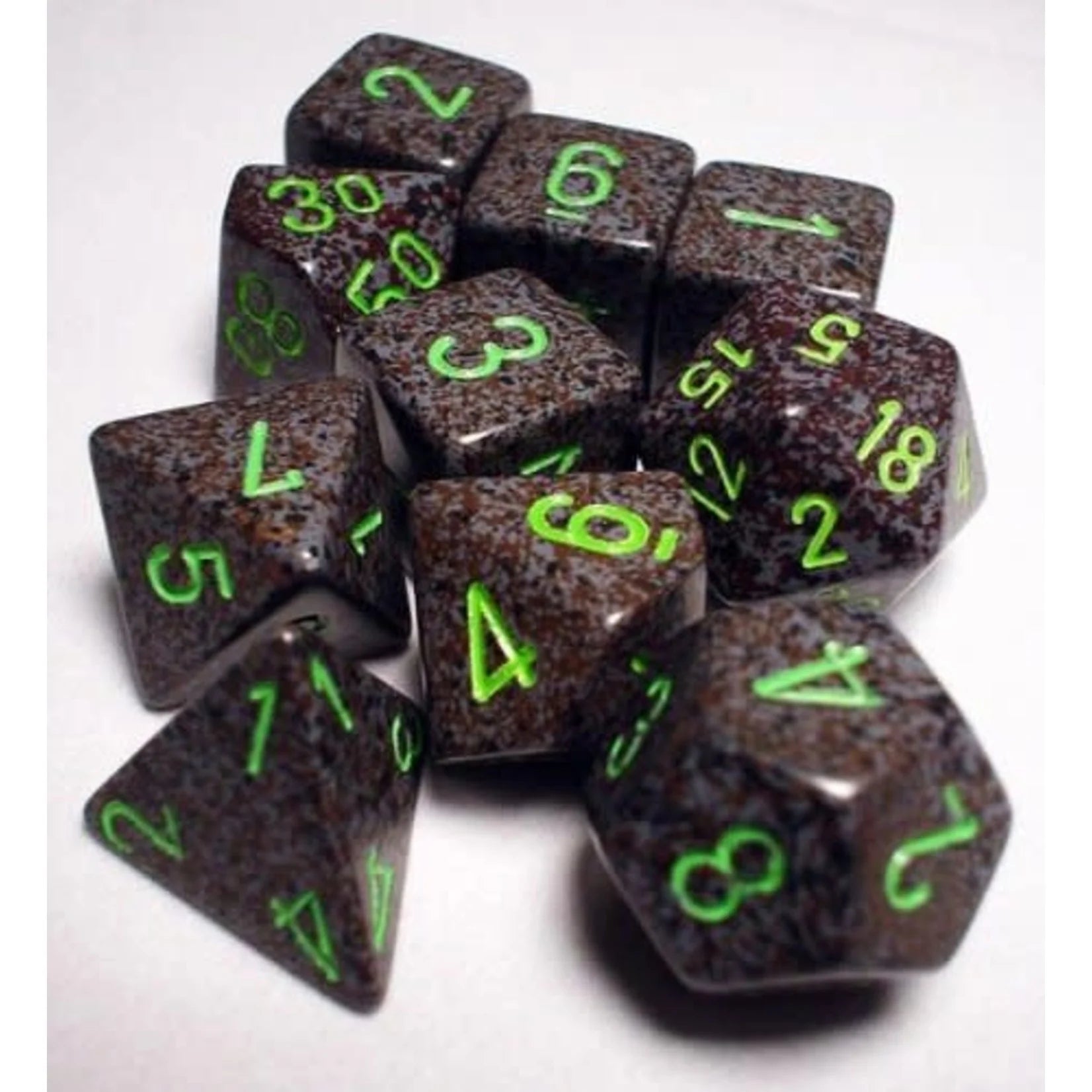 Speckled polyhedral dice set in earthy tones with bright green numbers, featuring seven unique shapes for gaming.