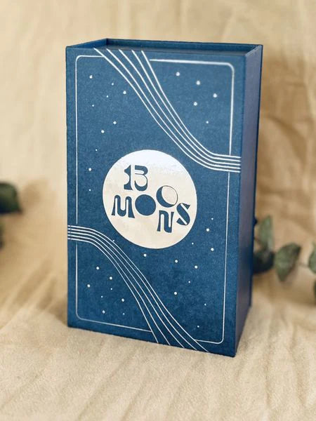 Blue box for the game "13 Moons: A Celestial Adventure!" featuring a circular logo and celestial design elements.