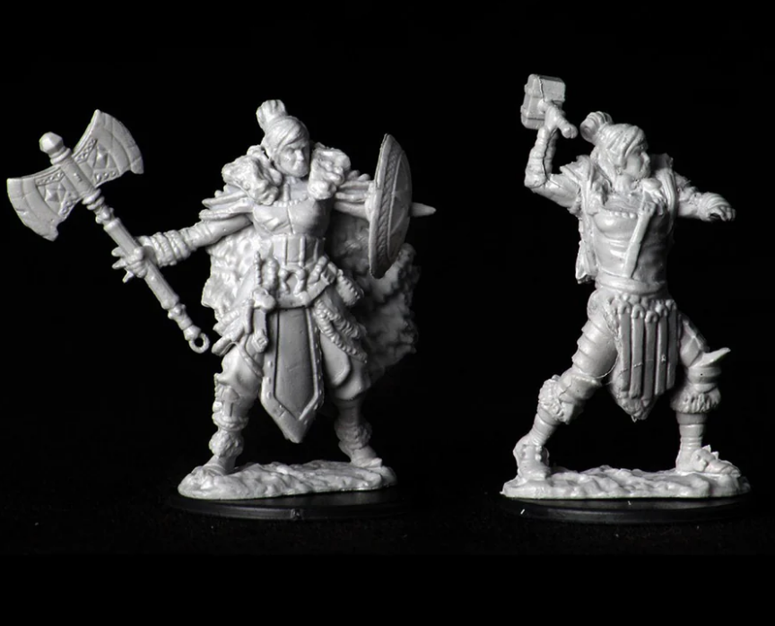Unpainted miniatures of a female half-orc barbarian wielding an axe and shield, showcasing detailed sculpting for tabletop gaming.