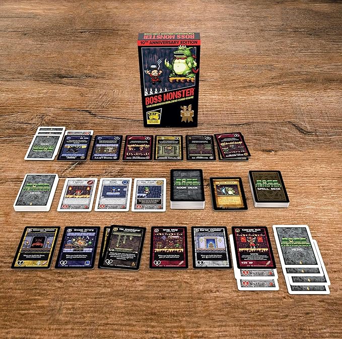 Boss Monster: 10th Anniversary Edition box with game cards and components displayed on a wooden surface.