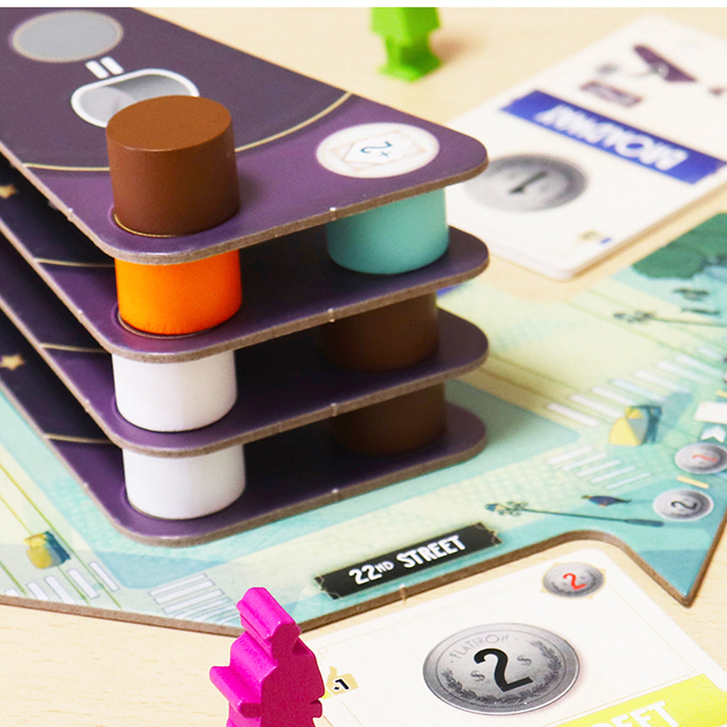 Colorful game pieces and cards from the Flatiron board game, featuring stacked tokens and a game board layout.