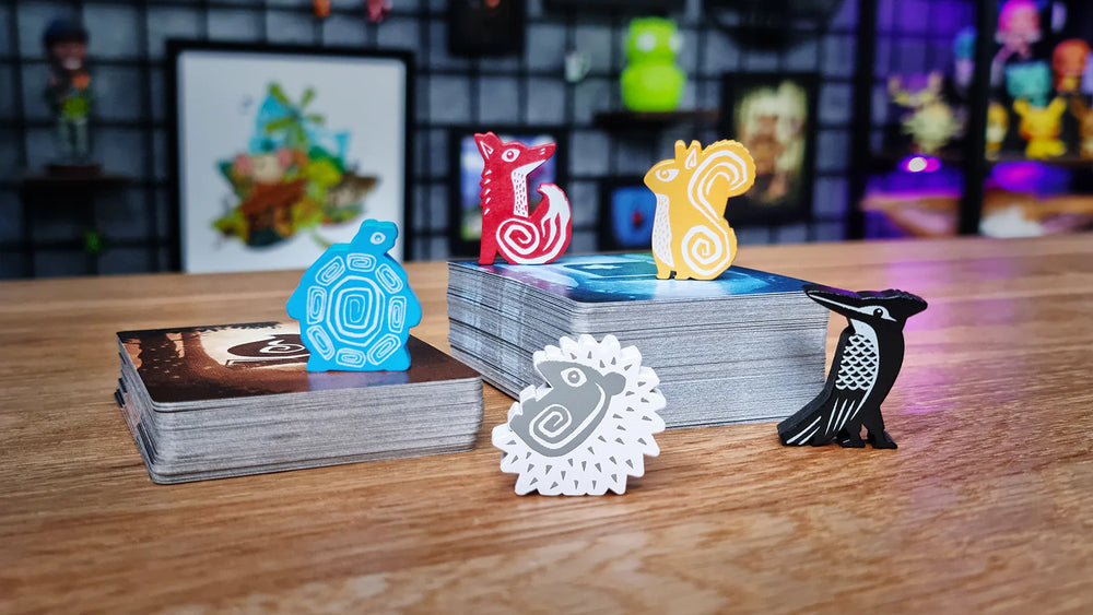 Colorful animal tokens including a turtle, fox, squirrel, and hedgehog on a tabletop with game cards in the background.