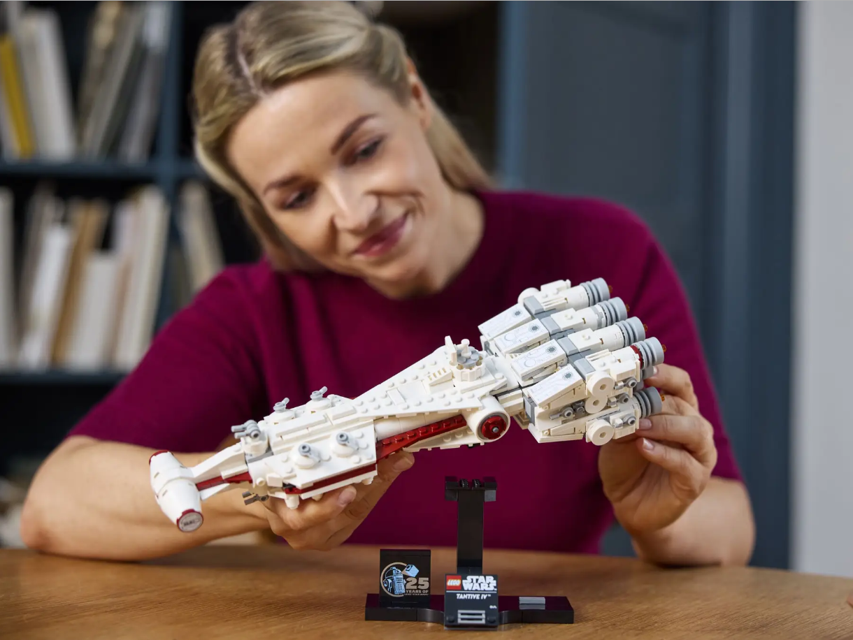 A woman examines the LEGO Star Wars Tantive IV model, showcasing its detailed design on a display stand.