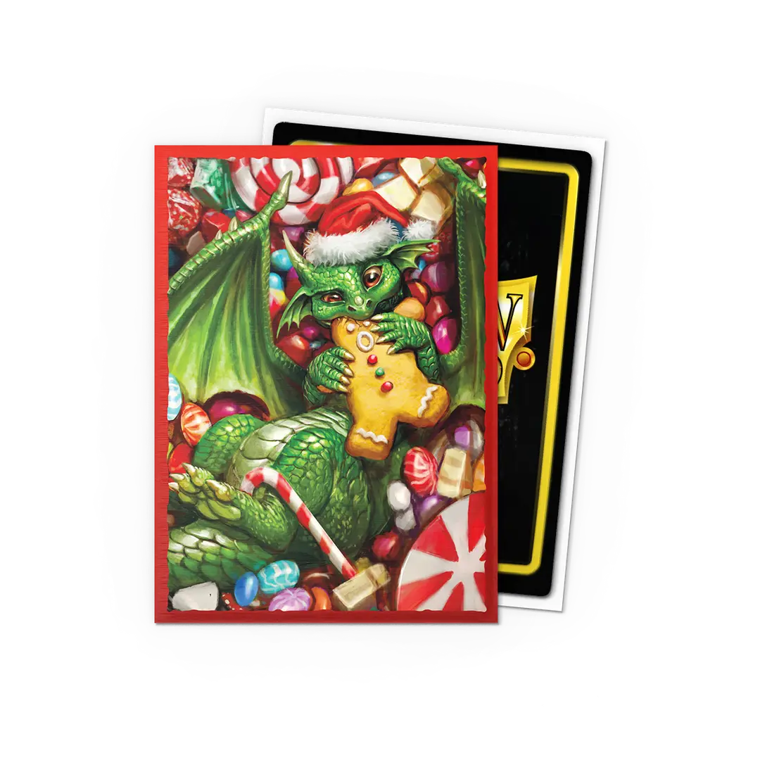 Dragon Shields Christmas 2024 features a green dragon in a Santa hat holding a gingerbread cookie amidst festive candies.
